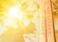 Extremely high temperature on thermometer against orange sky on sunny day. Severely hot summer weather