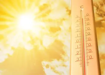 Extremely high temperature on thermometer against orange sky on sunny day. Severely hot summer weather