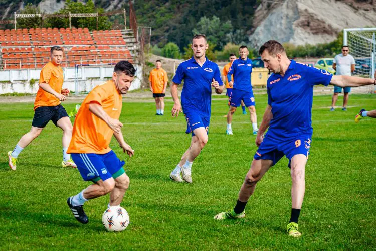 Fotbaliști în echipamente albastre și portocalii dispută mingea