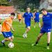 Fotbaliști în echipamente albastre și portocalii dispută mingea