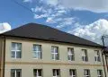 Clădire cu două etaje, acoperiș negru și cer senin