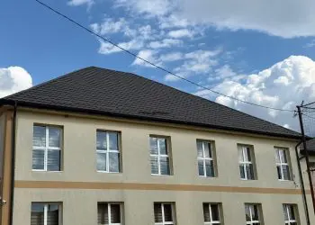 Clădire cu două etaje, acoperiș negru și cer senin