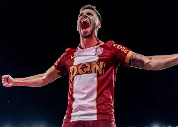 Fotbalist în tricou roșu sărbătorind cu brațele întinse