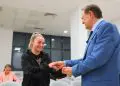 Bărbat în costum felicită o tânără într-o sală