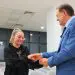 Bărbat în costum felicită o tânără într-o sală