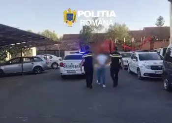 Polițiști escortează o persoană într-o parcare cu mașini