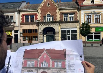 Arhitect ținând planul de restaurare în fața clădirii vizate de proiectul de modernizare din centrul istoric al municipiului Turda.