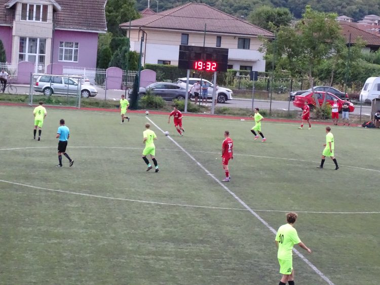 Meci de fotbal între echipe în galben și roșu