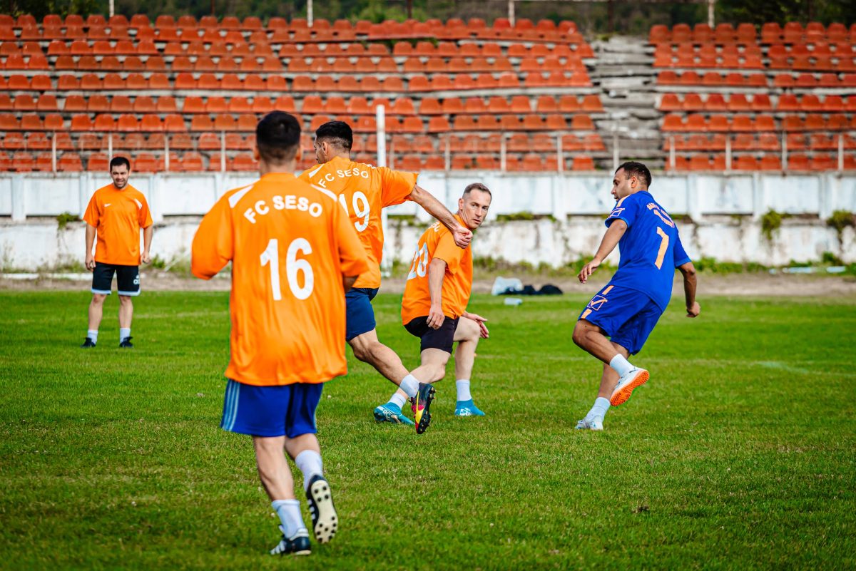 Fotbaliști în echipamente portocalii și albastre pe teren