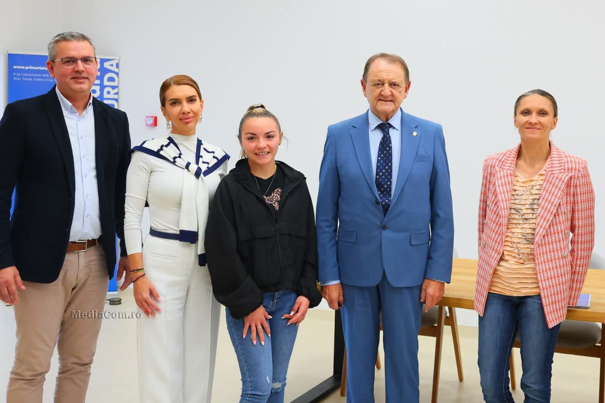 Cinci persoane pozează într-o sală de birou